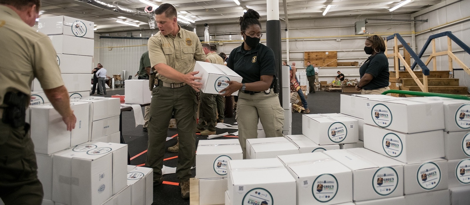 Serve and Connect members stacking boxes for the Greg's Groceries program